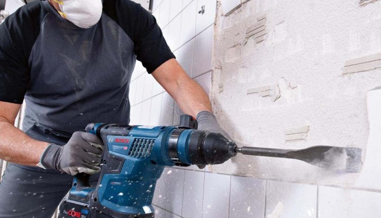 elektronarzędzia Bosch i Makita ustawione obok siebie na drewnianym stole warsztatowym