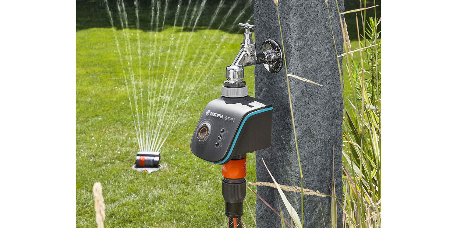 Automatyczny sterownik Gardena na trawniku obok zraszaczy podlewających trawę