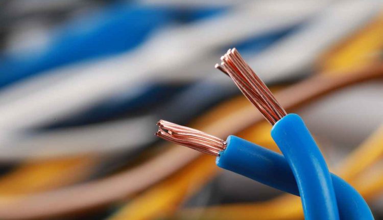 Elektryk w kombinezonie wymieniający przewody w mieszkalnym pokoju dziennym